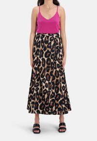 Rosa camisole i kombination med en leopardmönstrad maxikir med tan, svart och brun, som har en flödande design och mjuk textur. Svarta sandaler fulländar looken.