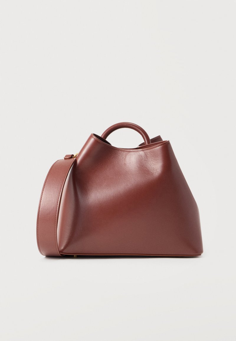 Καφέ λείο δερμάτινο τσάντα χειρός με δομημένο σχήμα, στρογγυλή χειρολαβή στο πάνω μέρος και φαρδιά αποσπώμενη ιμάντα ώμου σε λευκό φόντο.