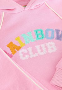 Rožinė džemperis su daugiakolorėmis išsiuvinėtomis raidėmis "RAINBOW CLUB", jaukus audinys ir baigtos rankovės. Akcento siuvinėjimas baltos spalvos.