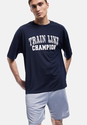 Camiseta deportiva de color azul marino con el texto blanco "ENTRENAR COMO UN CAMPEÓN", combinada con pantalones cortos de color gris claro, hechos de una tela suave y transpirable.