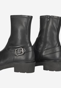 Bottines en cuir noir avec une fermeture éclair sur le côté, accent de boucle au niveau de la cheville et tige texturée, avec une semelle en caoutchouc épaisse.