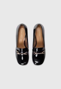 Mocasini din piele lacuită neagră cu vârf pătrat și detaliu cu cataramă de ton auriu pe partea superioară. Textură netedă și design minimalist.