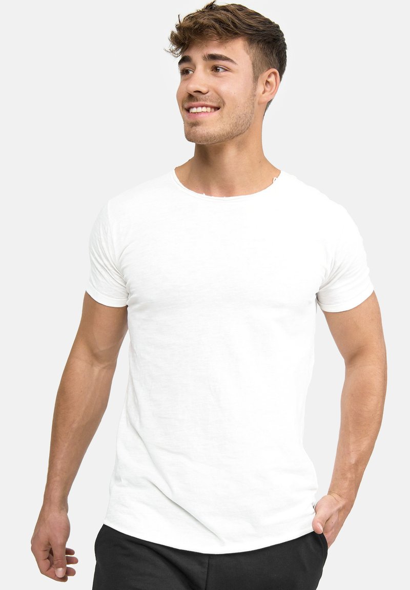 White cotton t-shirt with short sleeves, round neckline, and a relaxed fit. Smooth texture with minimal detailing. Worn with black pants.