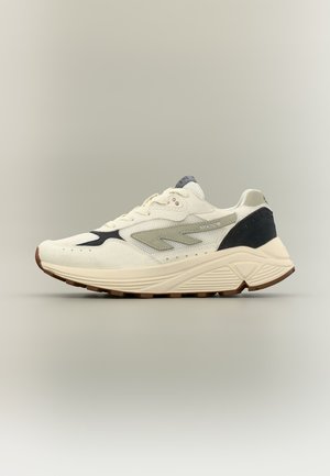 Krém színű atlétikai cipő szürke és fekete részletekkel, vastag talppal, hálós és velúr anyagból, oldalnézetből, egyszerű háttér előtt.