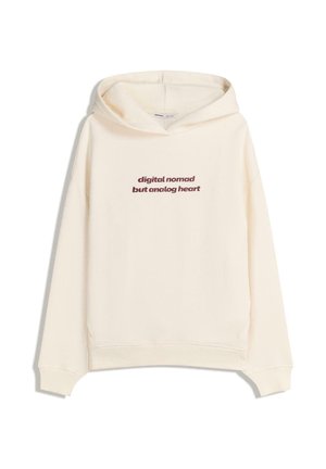 Krämfärgad hoodie med en kenguruficka. Har röd text: "digital nomad men analogt hjärta." Mjuk tyg, avslappnad passform och dragkedja på huvan.
