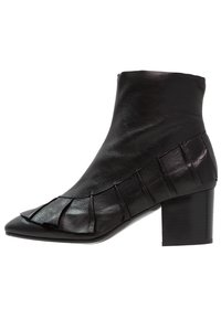Bottines en cuir noir avec bout pointu, accent froncé sur le côté et talon épais pour plus de stabilité. Texture lisse, design minimaliste.