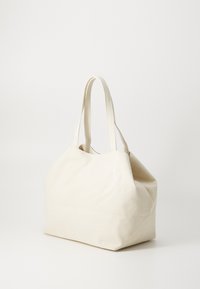 Canvas tote bag i off-white, med en strukturert form, to enkle håndtak og et minimalistisk design uten synlig maskinvare.