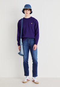 Violet ilgomis rankovėmis marškiniai, mėlyni džinsai, džinsinis skrybėlė, ir balti bateliai su raudonomis juostelėmis. Peties krepšys šviesiai mėlyno džinsinio audinio.