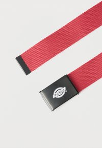 Κόκκινη υφασμάτινη ζώνη με μαύρη μεταλλική αγκράφα που φέρει το λευκό λογότυπο Dickies σε απλό λευκό φόντο.