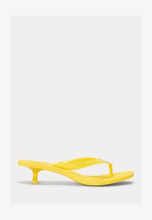 Geltoni atviri sandalai su pakulnėle, žemu smailiu kulnu ir lygiu, blizgiu paviršiumi, matomi šone ant balto fono.