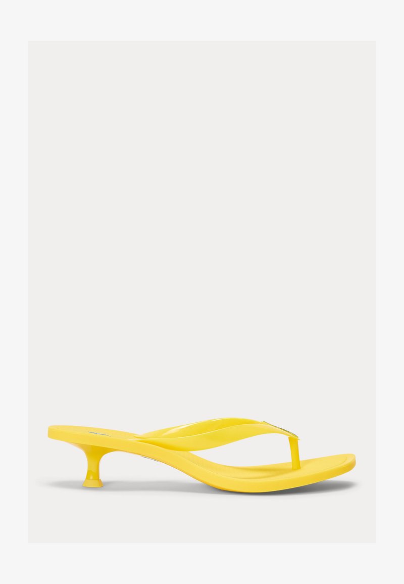 Sandale à talon jaune avec lanière en forme de tongs, petit talon kitten bas et finition lisse et brillante, vue de profil sur un fond blanc.