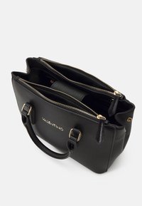 Svart läderhandväska med guldfärgad hårdvara, dubbla dragkedjefack och korta handtag; har en slät textur och prägling med logotyp.