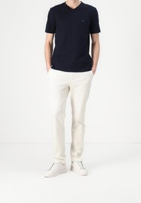 Námořnické tričko s V-výstřihem a malým logem, kombinované s krémovými chinos a bílými teniskami. Hladký materiál a volný střih.
