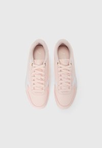 Un paio di scarpe da ginnastica Puma rosa chiaro con strisce laterali e lacci bianchi, viste direttamente dall'alto su uno sfondo bianco uniforme.
