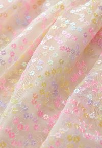 Tejido transparente con un suave tono rosa, decorado con lentejuelas florales iridiscentes en colores pastel, que presenta una delicada malla texturizada.