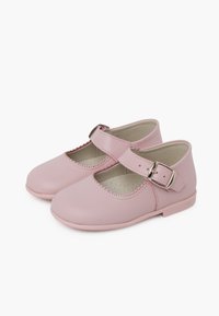 Zapatos Mary Jane de cuero rosa con bordes ondulados, correa ajustable y suela plana. Diseño resistente y textura suave.