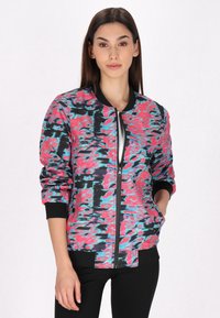 Bomberjack in abstract rood, zwart en teal patroon. Voorzien van een rits aan de voorkant, geribbelde manchetten en een effen zwarte halslijn.