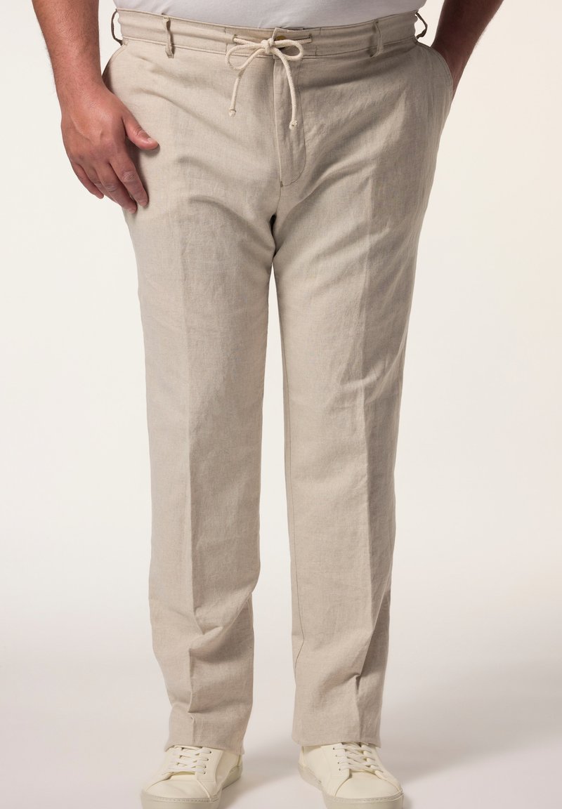 Leinenhose in Hellbeige mit Kordelzugbund, geradem Bein und seitlichen Taschen, kombiniert mit weißen Sneakern.