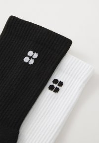 Calcetines acanalados en blanco y negro, con un pequeño patrón de cuatro puntos en colores contrastantes en cada calcetín.