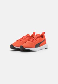 Scarpe da ginnastica a rete rosse con accenti neri e suola bianca. Presentano lacci e una linguetta sul tallone per un facile indossamento.