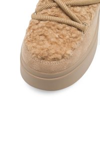Adidași bej cu un toc din țesătură pufoasă, accente de suede neted și talpă groasă din cauciuc. Sireturi împletite care se potrivesc cu materialul superior.