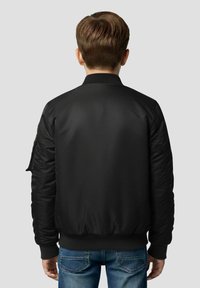 Bomber nero con finitura liscia, polsini e vita a coste. Presenta tasche laterali e una toppa sulla manica sinistra.