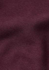 Tessuto bordeaux con una fine trama a coste, che mostra pieghe e una caduta morbida. Il materiale appare leggero e liscio.