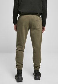 Olivengrønne sweatpants med slim fit, der har en elastisk talje, ribbede manchetter og en enkelt baglomme. Glat tekstur.