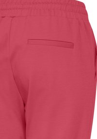 Pink joggers with a smooth texture, featuring an elastic waistband and a back pocket. Simple design with no visible patterns or accents.