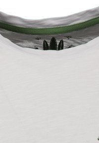 Camiseta blanca de cuello redondo con un cuello interior verde y un logotipo o diseño negro visible dentro del escote.