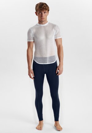 Hvid mesh kortærmet top med rund halsudskæring, båret over mørkeblå tætsiddende leggings; minimal struktur, letvægtsmateriale.