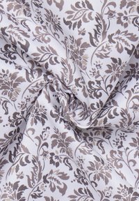 Weißer Stoff mit einem detaillierten braunen Blumenmuster, das wirbelnde Blätter und Blüten zeigt und eine subtile, strukturierte Oberfläche aufweist.