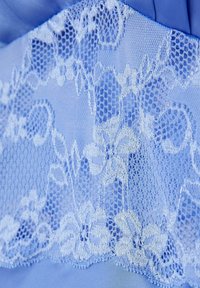 Tela azul claro con intrincados encajes con patrones florales y una fina textura similar a una red, superpuesta sobre una base suave de satén.