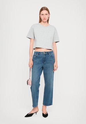 T-shirt grigio cropped con maniche corte, jeans dritti a vita alta blu, décolleté nere a punta e una piccola borsa a tracolla rosa.