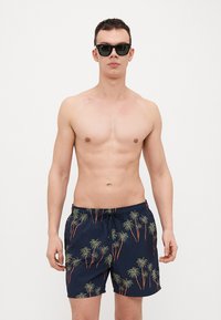 Shorts de bain marine avec un imprimé palmier en vert et orange, dotés d'une taille à cordon de serrage et d'un tissu léger et à séchage rapide.