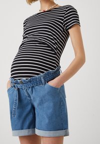 Svart och vit randig graviditetstopp matchad med ljusblå denimshorts, med uppvikta ärmar och bälte i midjan. Slät textur, avslappnad passform.