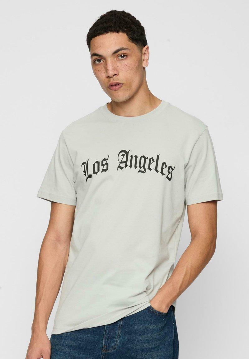 Šviesiai pilkas medvilnės marškinėliai su trumpomis rankovėmis, su juodu tekstu "Los Angeles" drąsiais gotikinių šriftu. Kasdienis stilius.