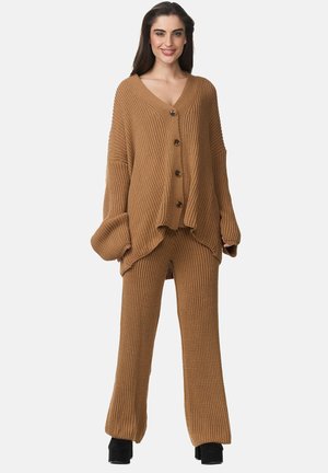 Set di cardigan e pantaloni abbinati in maglia marrone con scollo a V, taglio oversize, cinque bottoni e texture a coste. Indossato con tacchi a piattaforma.