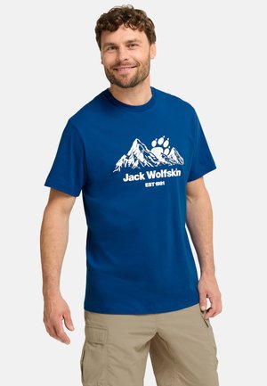 Blaues Baumwoll-T-Shirt mit weißem Bergmotiv und dem Text "Jack Wolfskin EST 1981." Rundhalsausschnitt und kurze Ärmel. Lässige Passform.