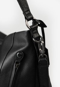 Borsa in pelle nera con finitura texturizzata, dotata di minuteria metallica, una tasca con zip e una tracolla regolabile con moschettone.