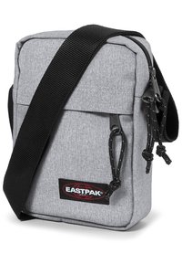 Grå tygaxelväska med svart justerbar rem, dragkedjestängning och Eastpak-logotyp på framsidan. Strukturerad yta.