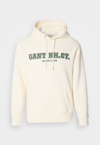 Krémová mikina s kapucňou, s klokankou, zaväzovaním na kapucni a zeleným potlačou "GANT NH. CT." a "SPORTS CLUB" na prednej strane.