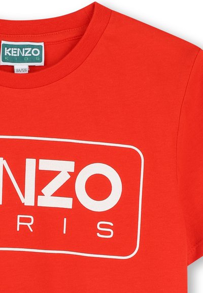 Rode katoenen t-shirt met een groot wit rechthoekig logo met "KENZO" boven "PARIJS," korte mouwen en een ronde hals.