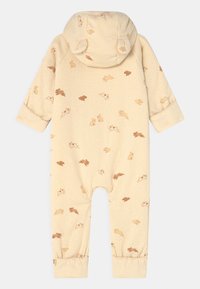 Beige barnoverall med kanintryck i brunt och tan, med huva och elastiska ärmslut vid anklarna. Mjukt tyg med en strukturerad mönster.
