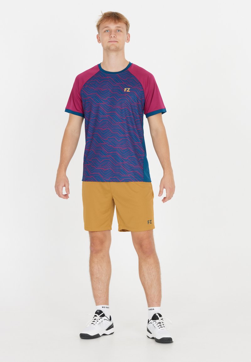 Kortärmad atletisk skjorta i mörkblått och vinrött med vågigt mönster, kombinerat med gyllene shorts, med en logotyp på båda plagg.