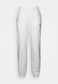 Weiße Jogginghosen mit elastischem Bund, seitlichen Taschen und Knöchelriemchen, mit einem kleinen schwarzen Lacoste-Logo auf dem Oberschenkel.