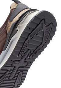 Zapatillas de ante y cuero marrón con una suela de goma negra texturizada, que presenta ranuras y un diseño elegante para una mejor tracción.