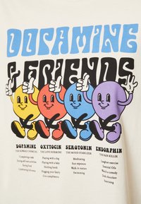 Ljusfärgad t-shirt med tecknade figurer i livliga färger: gul, röd, blå, lila. Texten framhäver kemiska termer med aktiviteter listade nedanför.