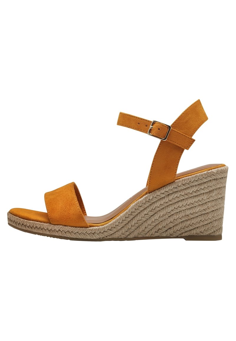 Sandales compensées en suède jaune avec une large sangle avant et une sangle de cheville, dotées d'une boucle en argent. La semelle compensée est recouverte d'une texture en corde tissée.
