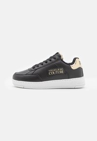 Svarta lädersneakers med vit gummisula, guld detaljer på hälen och "VERSACE JEANS COUTURE"-logotyp på sidan.